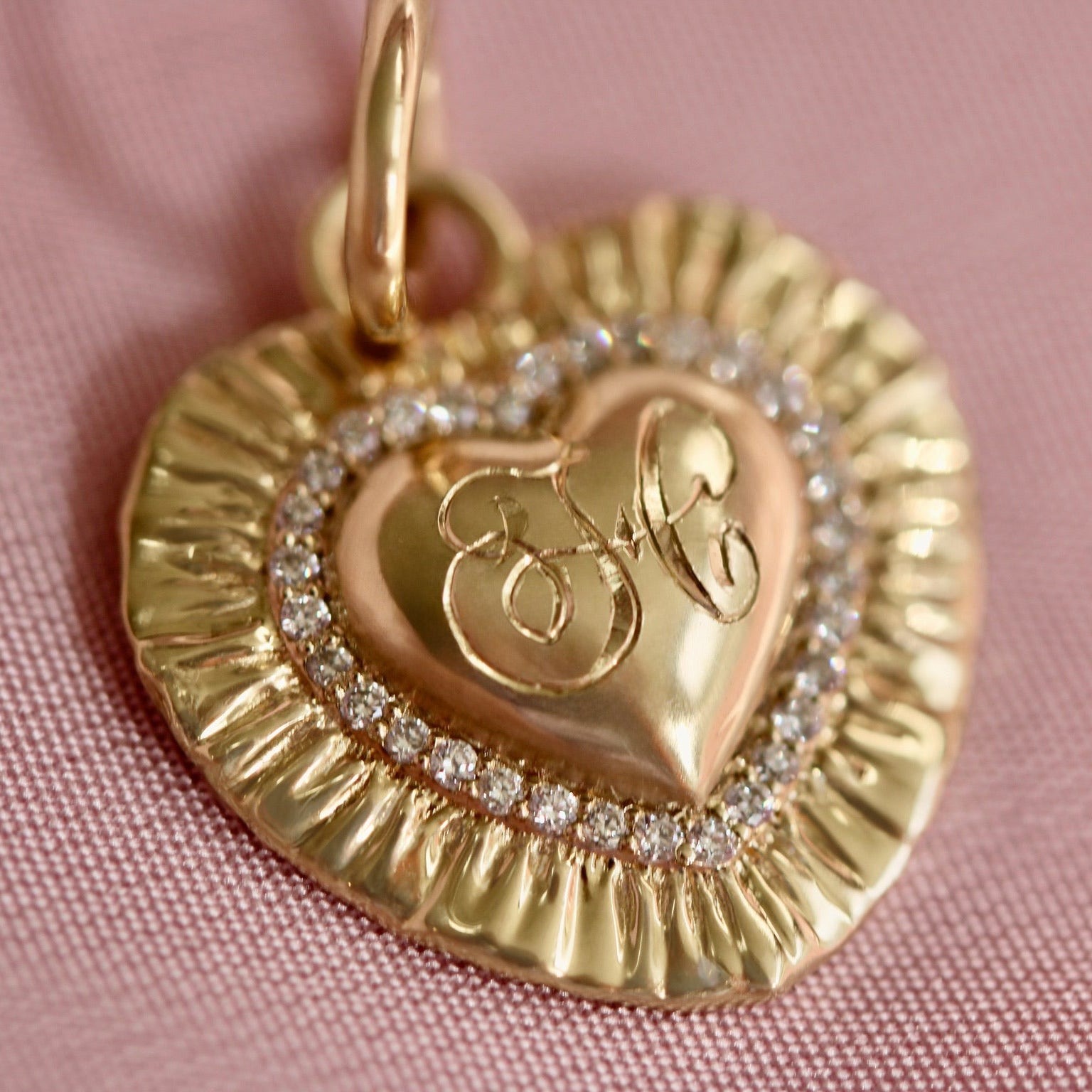 Gold heart-shaped pendant with initials on a pink background